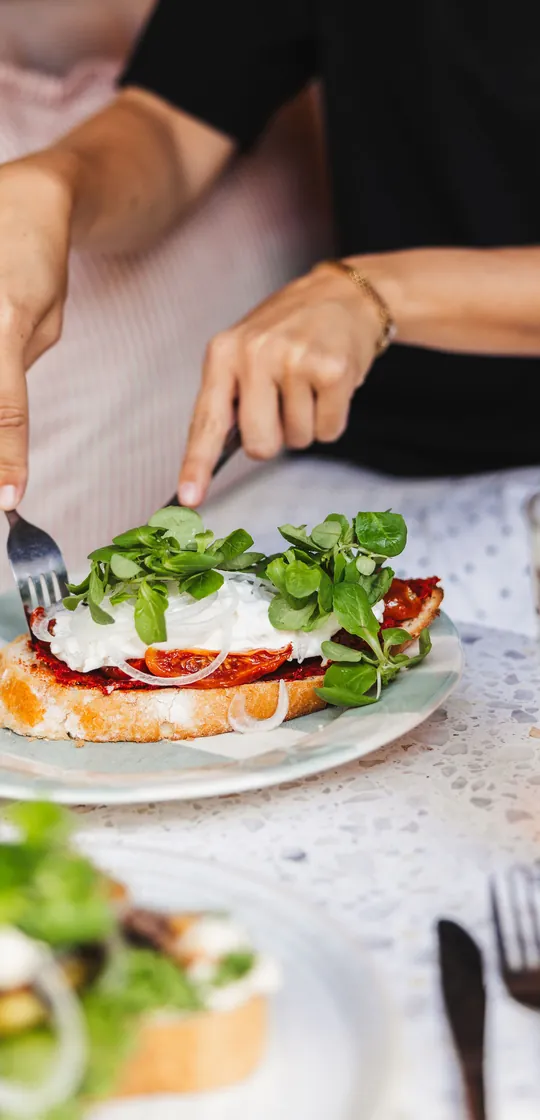 Makka med burrata, tomat och ärtskott som skärs upp